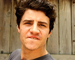 A head shot of a young man facing the viewer. He has a perplexed look on his face.